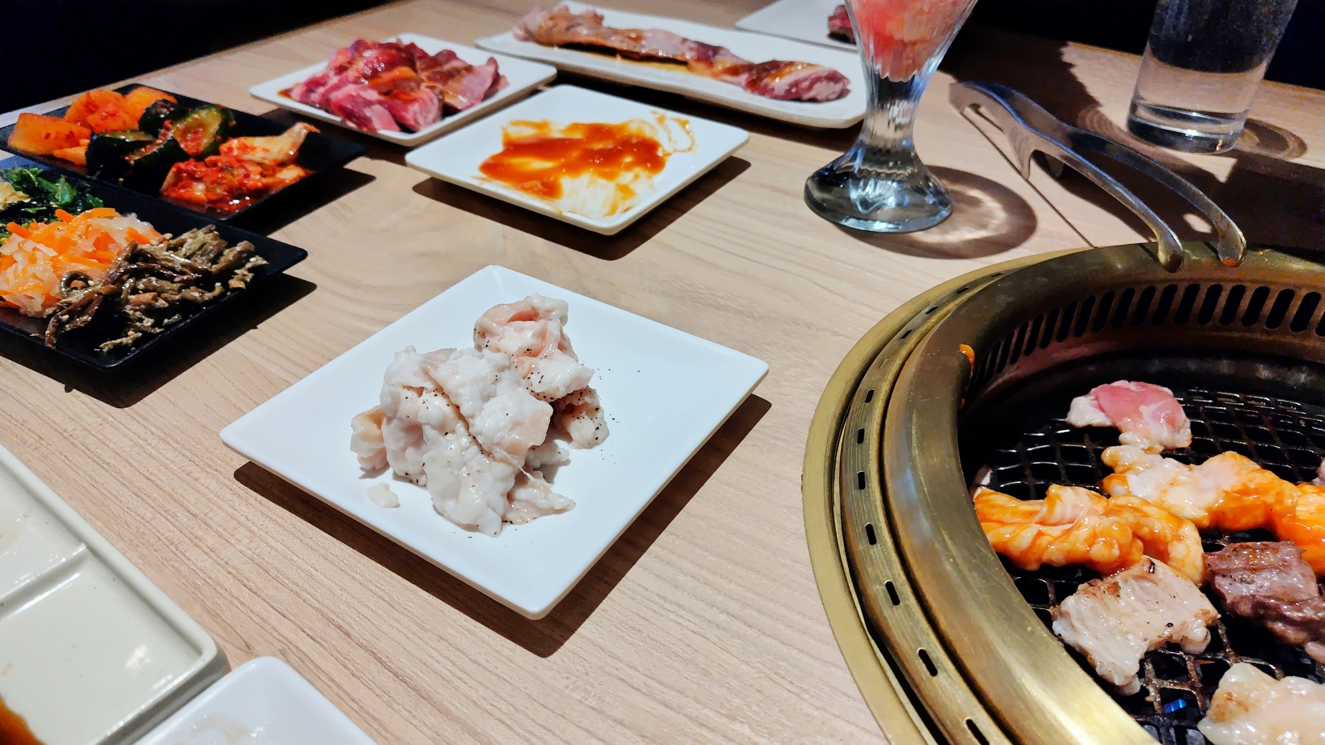 焼肉店のテーブルに並ぶ網焼き肉とサイドメニュー