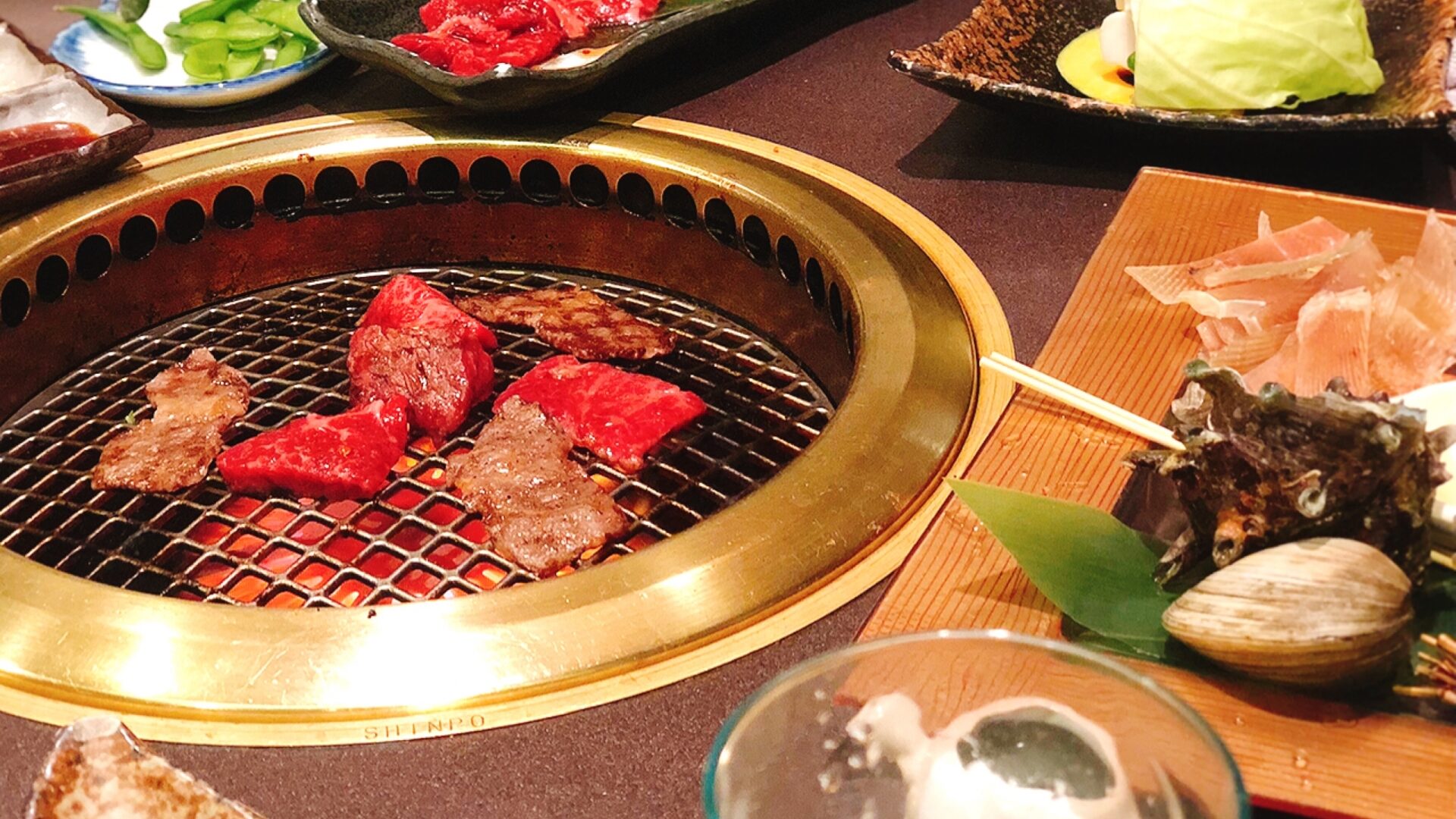 焼肉店のテーブルに並ぶ網焼き肉とサイドメニュー